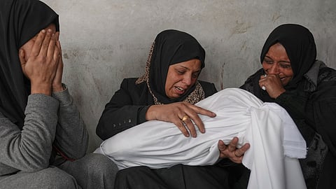 Naanaa Abu Aker holds the body of her 2-year-old niece Salma, killed during an Israeli army strike, before their burial at the Baptist hospital in Gaza City, Monday March 24, 2025.