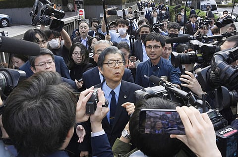 Nobuya Fukumoto, foreground center, a lawyer for the Unification Church, is surrounded by reporters after the church was ordered dissolved by the Tokyo District Court, in front of the court in Tokyo Tuesday, March 25, 2025.