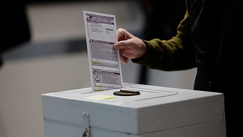 A man places his ballot in a box during early voting in Waukesha, Wis Tuesday, March 18, 2025.