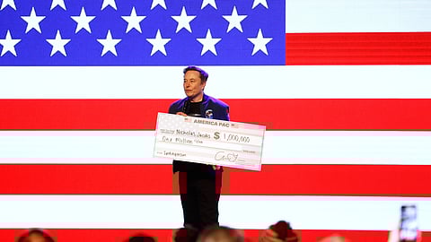 Elon Musk holds a check for $1 million dollars at a town hall Sunday, March 30, 2025