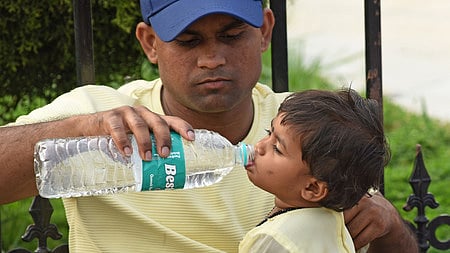 A father pacifying his child's thirst on a sweltering afternoon in Bengaluru 
