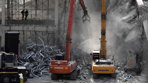 Soldiers from fire services spray water to settle the dust as heavy machineries are deployed to clear the rubble from an under construction high-rise building that collapsed after Friday's earthquake in Bangkok, Thailand, Wednesday, April 2, 2025.