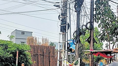 Discom personnel fix an electricity pole to restore power supply in Hyderabad.
