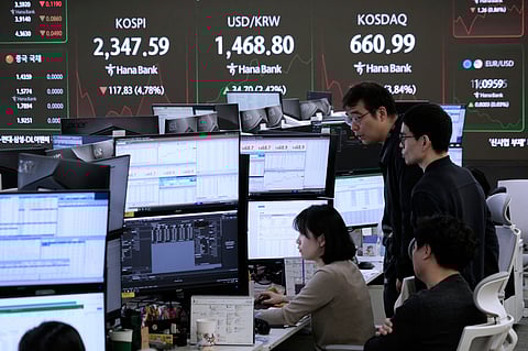 Currency traders watch monitors near a screen showing the Korea Composite Stock Price Index (KOSPI), top left, and the foreign exchange rate between U.S. dollar and South Korean won, top center, at the foreign exchange dealing room of the KEB Hana Bank headquarters in Seoul, South Korea, Monday, April 7, 2025. 
