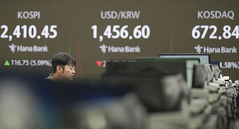 A currency trader walks by the screens showing the Korea Composite Stock Price Index (KOSPI), left, the foreign exchange rate between U.S. dollar and South Korean won and the Korean Securities Dealers Automated Quotations (KOSDAQ) at a foreign exchange dealing room in Seoul, South Korea, Thursday, April 10, 2025. 