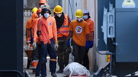 Rescue workers stand next to a recovered body of a victim who died when the roof collapsed two nights prior at the Jet Set nightclub during a merengue concert, in Santo Domingo, Dominican Republic, Wednesday, April 9, 2025.