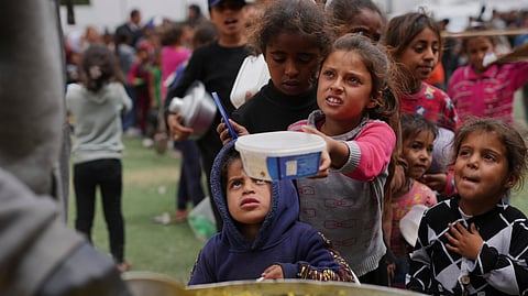 Palestinian children receive donated food at a distribution center in Nuseirat, central Gaza Strip, Friday, April 11, 2025.