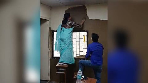 Video showing the principal coating walls of the classroom with cow dung.