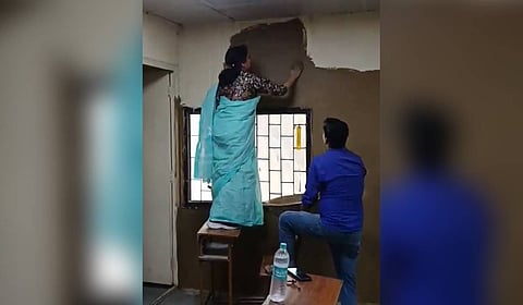 Video showing the principal coating walls of the classroom with cow dung.