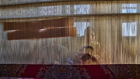 Shameema and her husband, Mohammad Yousaf Dar, weave a Kashmiri hand-knotted carpet at their home in Srinagar on April 15, 2025. 