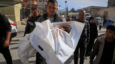 A Palestinian man carries the body of his niece, who was just days away from her first birthday, into Nasser Hospital, after their home was hit by an overnight Israeli airstrike in Khan Younis, southern Gaza Strip, on Wednesday, April 16, 2025