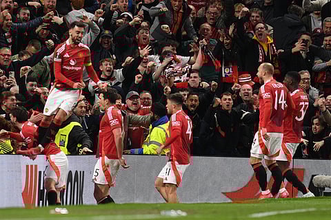 Manchester United's English defender #05 Harry Maguire (2L) and teammates celebrate with their fans after Maguire scores their fifth goal during the UEFA Europa league quarter-final, second leg football match between Manchester United and Lyon on April 17, 2025.