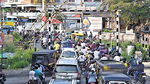 Vehicles jostle to cross over as the railway gate at Kureekad opens after a train passes on Sunday evening 