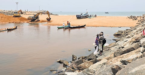 Dredging in progress to cut open the sandbar at Muthalapozhi harbour mouth in Perumathura