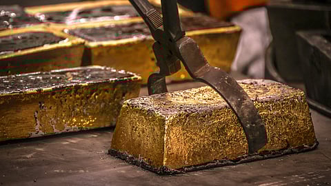 A worker places a 20-kilogram gold brick on a tray after it is removed from a cast at a refinery in Sydney on August 5, 2020.