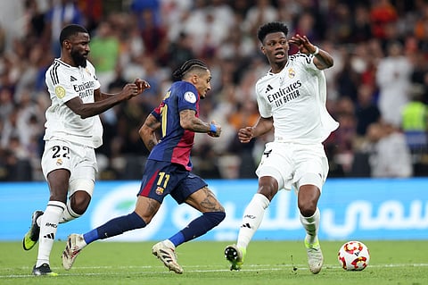 Barcelona's forward #11 Raphinha runs with the ball past Real Madrid's midfielder #14 Aurelien Tchouameni defender #22 Antonio Ruediger during the Spanish Super Cup final football match between Real Madrid and Barcelona on January 12, 2025.