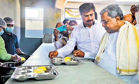 Chief Minister Siddaramaiah samples chow chow bath during the inauguration of a new Indira Canteen outlet, in Hanur, Chamarajanagar district, on Friday.