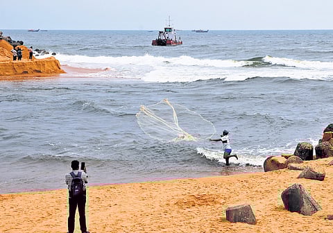 The dredger brought from Azheekal anchored in the sea at Muthalapozhi in Thiruvananthapuram on Saturday. Nearby, a fisherman casts his net in the recently opened estuary 