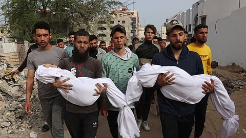 Palestinians carry shrouded bodies of relatives, killed in an Israeli strike on a school-turned-shelter, during their funeral near the Al-Shifa hospital in Gaza City on April 23, 2025.
