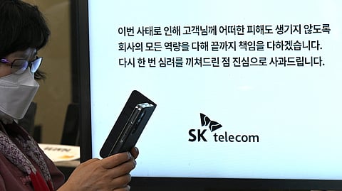 A woman uses her mobile phone while waiting to replace her USIM ship in front of an SK Telecom branch in Seoul on April 28, 2025. 