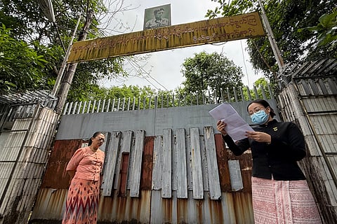 An auction official reads a statement outside the gate of the family house of detained Myanmar civilian leader Aung San Suu Kyi in Yangon on April 29, 2025,