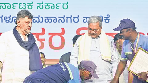 Civic workers seek Chief Minister Siddaramaiah’s blessings, as Deputy Chief Minister DK Shivakumar looks on, at an event on Palace Grounds on Thursday