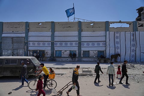 Palestinians walk next to the closed humanitarian aid distribution center of UNRWA, the U.N. agency helping Palestinian refugees in Jabaliya, Gaza Strip on Tuesday, April 29, 2025. 