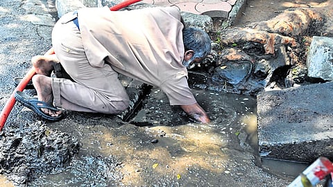 A corporation sanitation worker cleaning the drains in front of the Secretariat in Thiruvananthapuram on Saturday, following Friday’s heavy rain, without essential protective gear like gloves and boots, despite health risks 