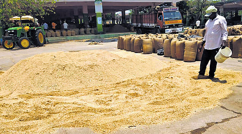 A farmer dries rain-soaked paddy at the market yard in Nizamabad on Tuesday