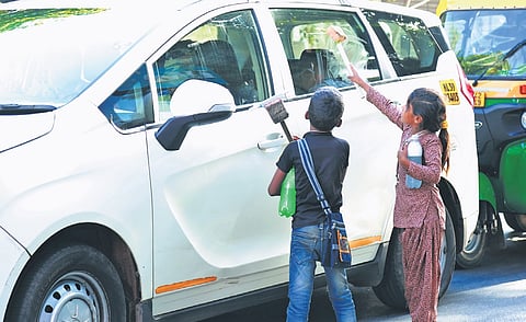 Nomadic children seeking money after cleaning the window of a car 