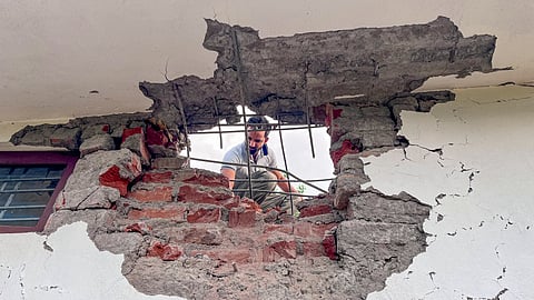 A man looks through a damaged portion of a house after heavy firing and shelling by the Pakistan military overnight across the Line of Control and International Border in the Mendhar area of the Poonch district, Jammu and Kashmir, on Wednesday, May 7, 2025.
