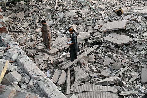 Locals stand on the debris of destroyed structures at the Government Health and Educational complex in Muridke about 30 kilometres from Lahore, on May 7, 2025, after Indian strikes.