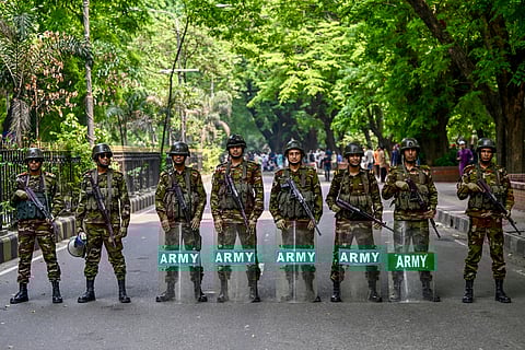 Bangladesh Army soldiers stand guard as protesters gather in front of the State Guest House Jamuna, the official residence of Bangladesh's Chief Advisor Office of Interim Government Muhammad Yunus.