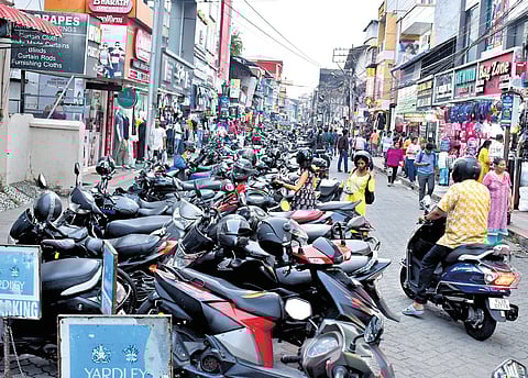 Two-wheelers parked in multiple rows along the narrow Broadway