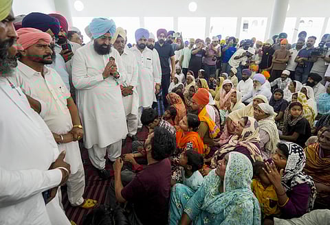 Congress leader Partap Singh Bajwa meets relatives of the hooch tragedy victims, gathered at a gurudwara to meet Punjab CM Bhagwant Mann, at Marari Kalan village, in Amritsar district, Tuesday, May 13, 2025. 