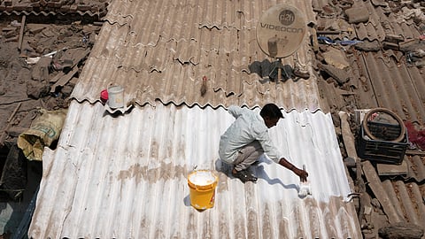 A man applies reflective paint to the roof of a house that helps keep the indoors cooler in Ahmedabad, India, Wednesday, April 2, 2025. 