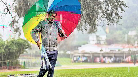 An umbrella seller shields himself from sudden showers in Ooty on Friday 