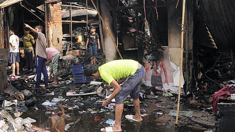 People look for their belongings amid charred debris after a fire broke out at a stone market at Kotla Mubarakpur area, in New Delhi, Wednesday, May 21, 2025