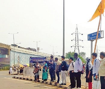 People waiting on the narrow median near Jagatpur Golei square.