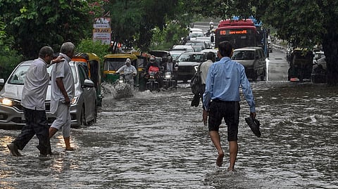 Pedestrians wade through the waterlogged road in Delhi.