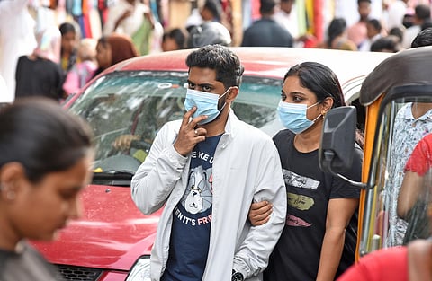 People walk with masks amid a rise in COVID-19 cases in Bengaluru on Saturday. 