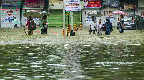 Mumbai: Pedestrians wade through an inundated road amid rains, in Mumbai, Monday, May 26, 2025.