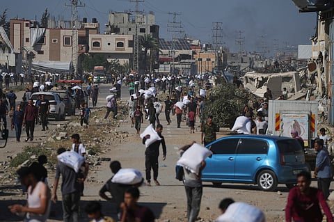 Palestinians carry bags of flour after storming a U.N. World Food Program warehouse in Zawaida, Central Gaza Strip, on Wednesday, May 28, 2025. 