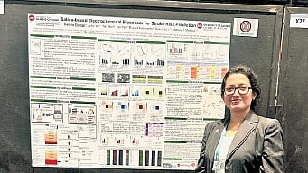 Haritha stands next to her doctoral project presentation