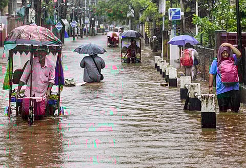 People wade through a waterlogged road during rainfall, in Guwahati, Assam on Friday.