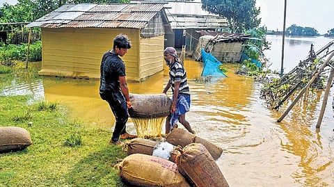Villagers shift rice sacks to other locations and people use a boat to move to safer areas after floods in Nagaon.