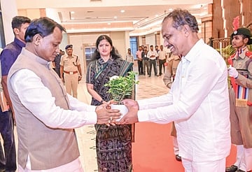 Majhi hands over a sapling to a person at the event on June 4, 2025. 