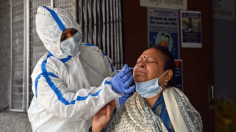 A health worker collects a nasal swab sample of a woman for the COVID-19 test amid a surge in cases.