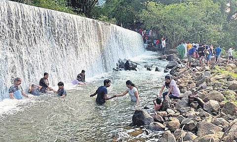 Tourists enjoy taking bath at a waterfall at Prakriti Gramam at Ezhattumukham