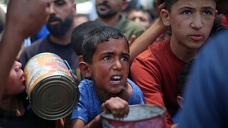 Palestinian children wait for food at a distribution point in Nuseirat, in the central Gaza Strip, on June 11, 2025.